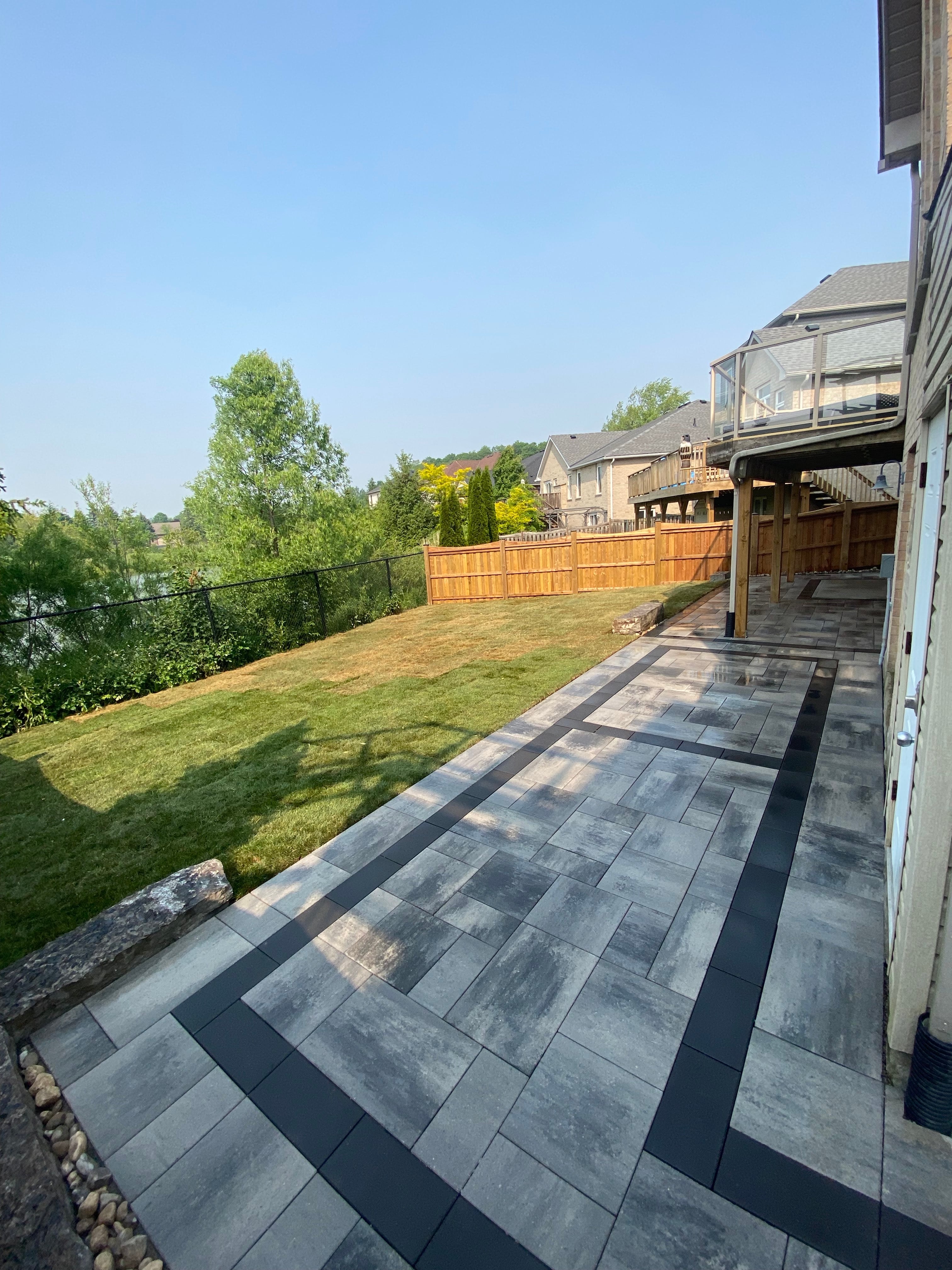 Guelph interlocking patio with charcoal border, new sod and privacy fence installed by BCI Landscaping