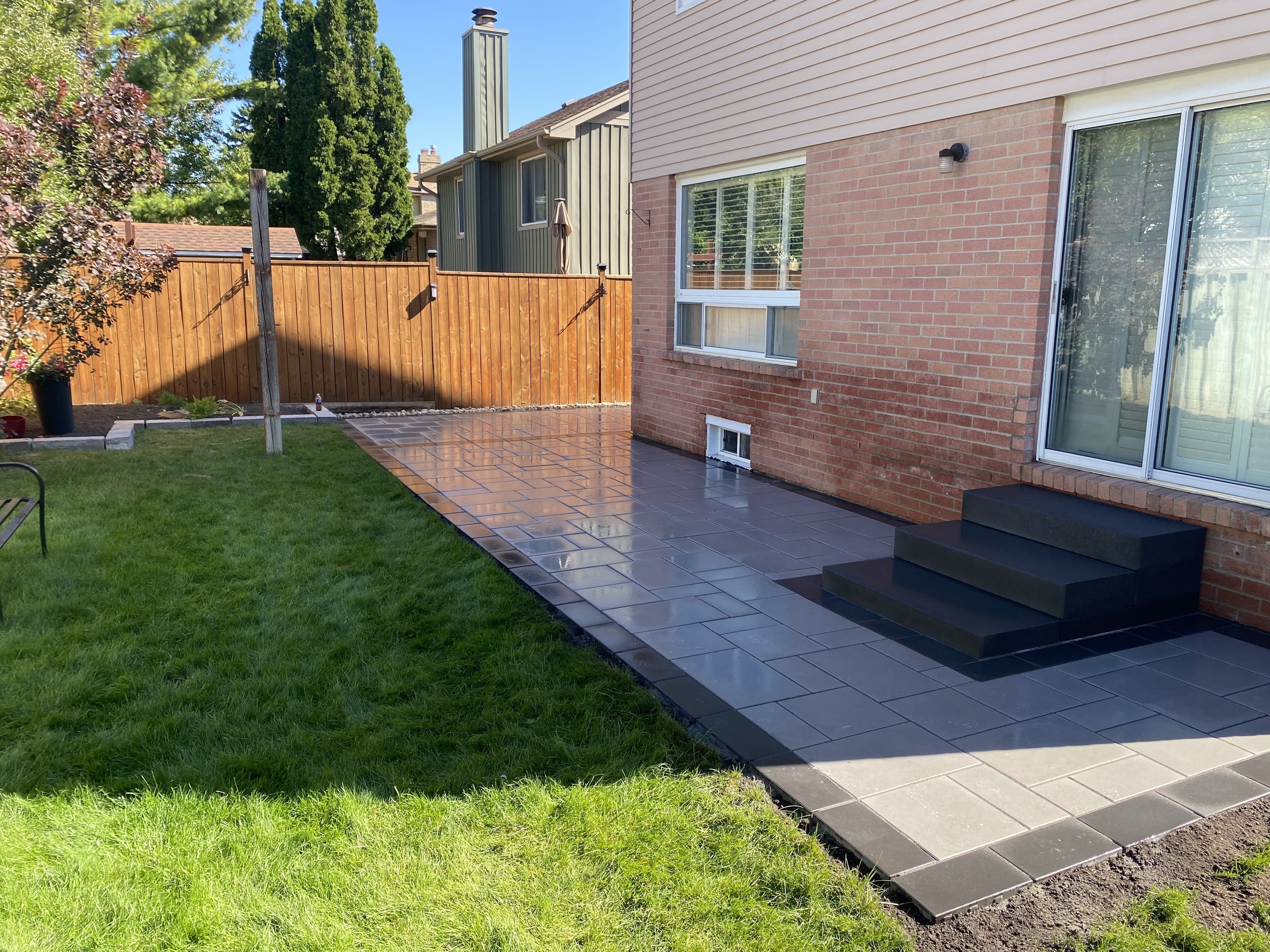 Guelph backyard patio living area with privacy fence and granite steps to back door by BCI Landscaping