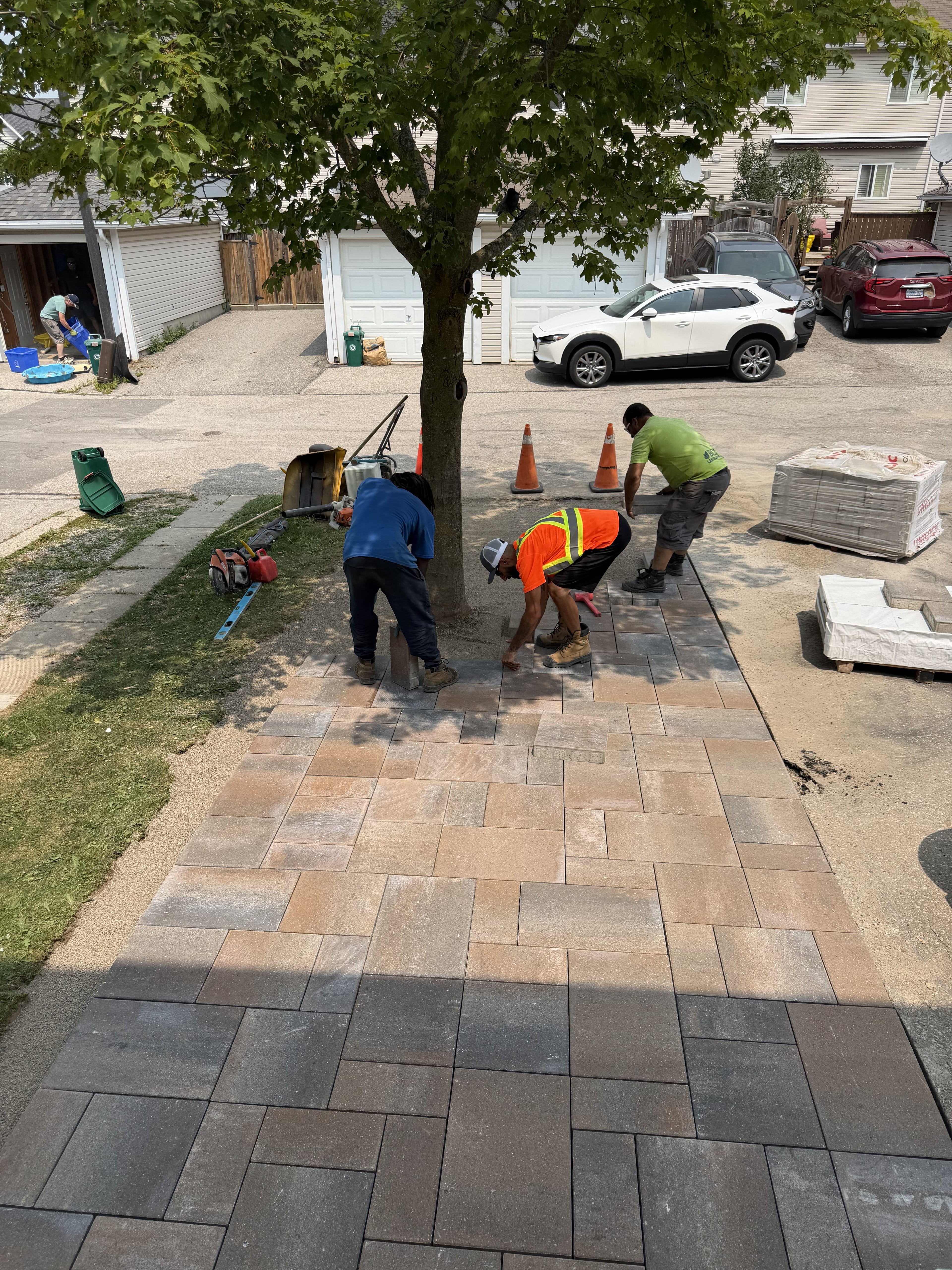 BCI Landscaping crew laying interlocking pavers during active installation, pool landscaping Guelph