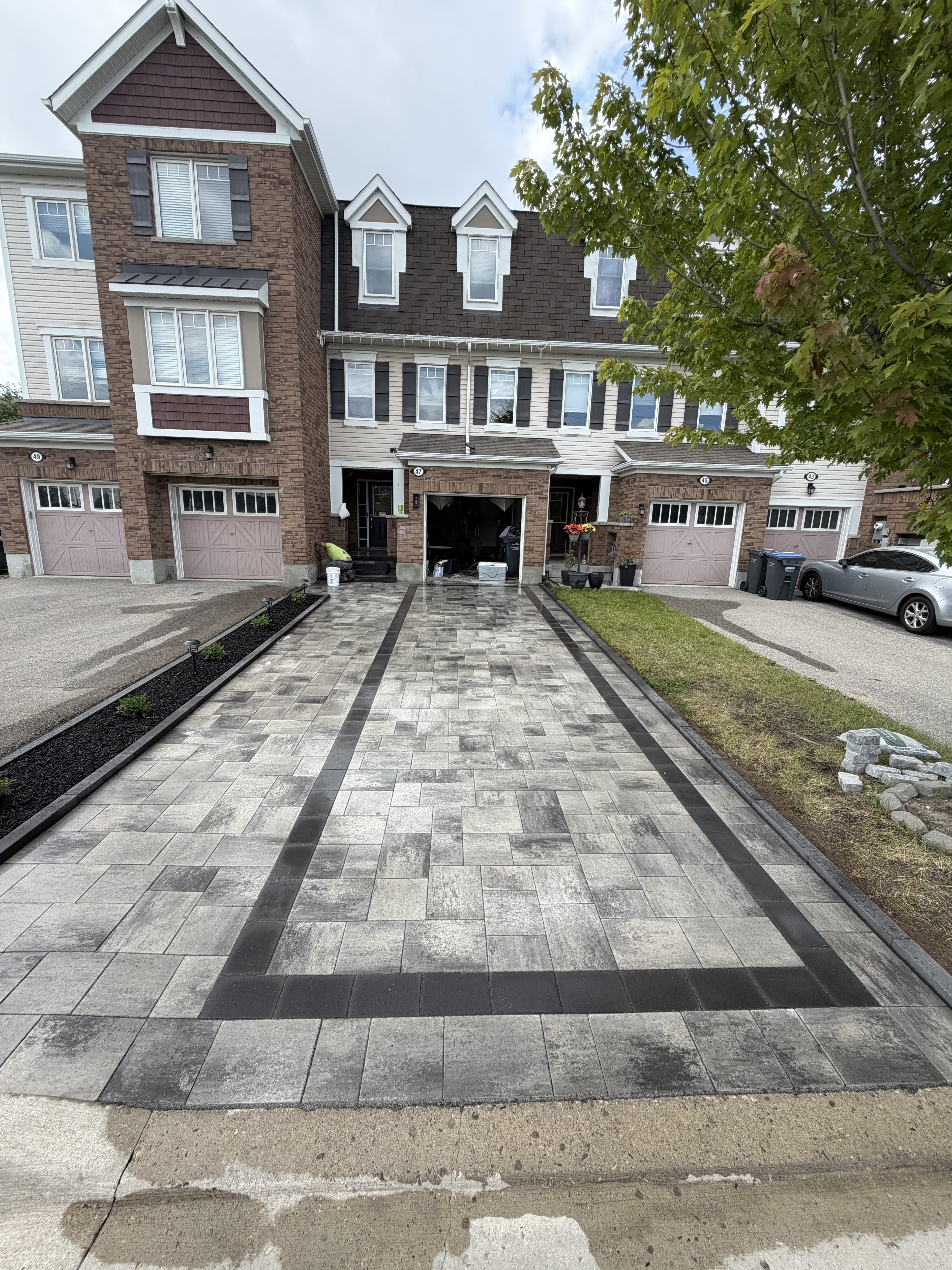 Completed interlocking driveway with charcoal border on a residential property, pool landscaping Guelph by BCI Landscaping