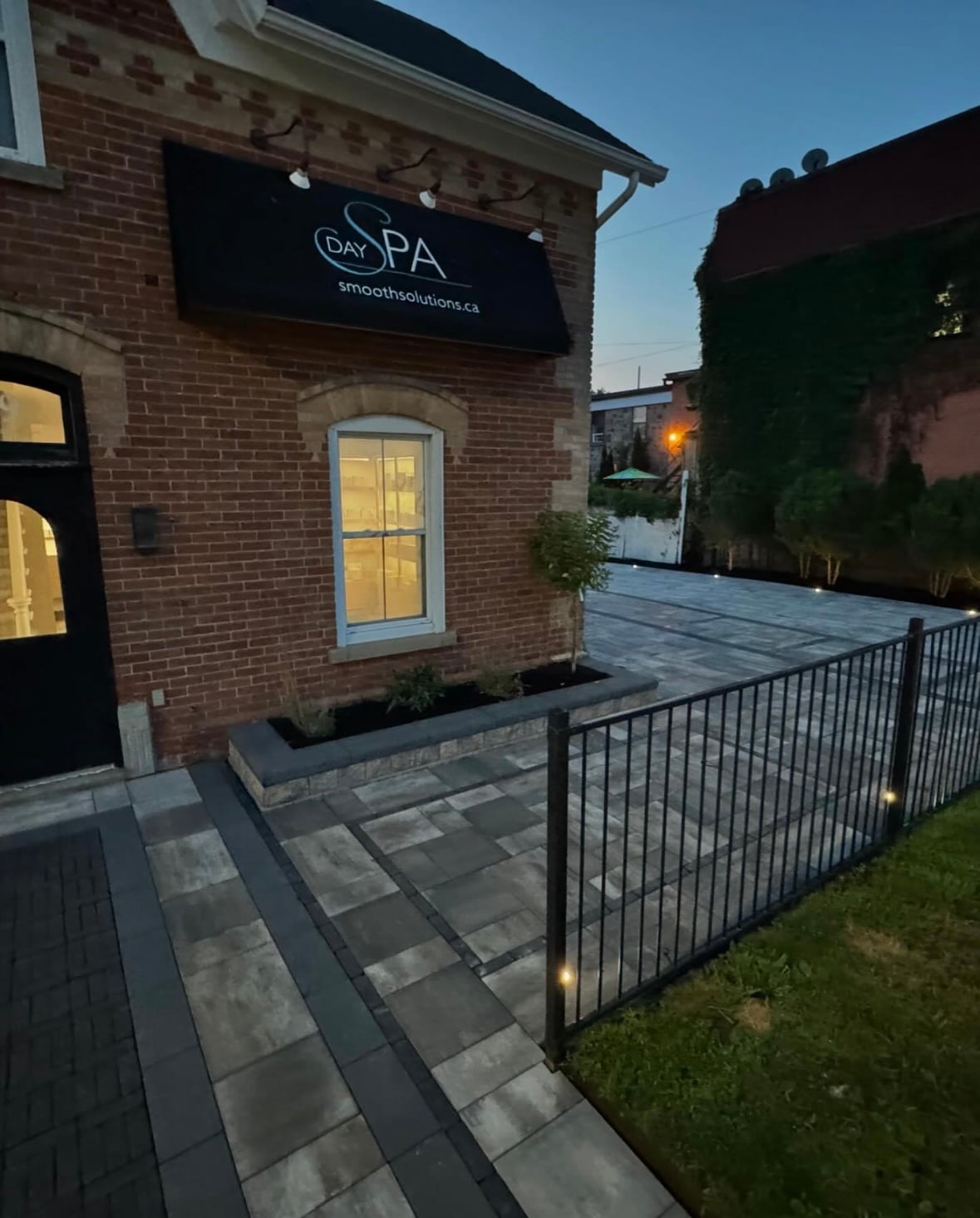 Commercial interlocking walkway and parking area with pathway lighting and wrought iron fence installed by BCI Landscaping in Guelph