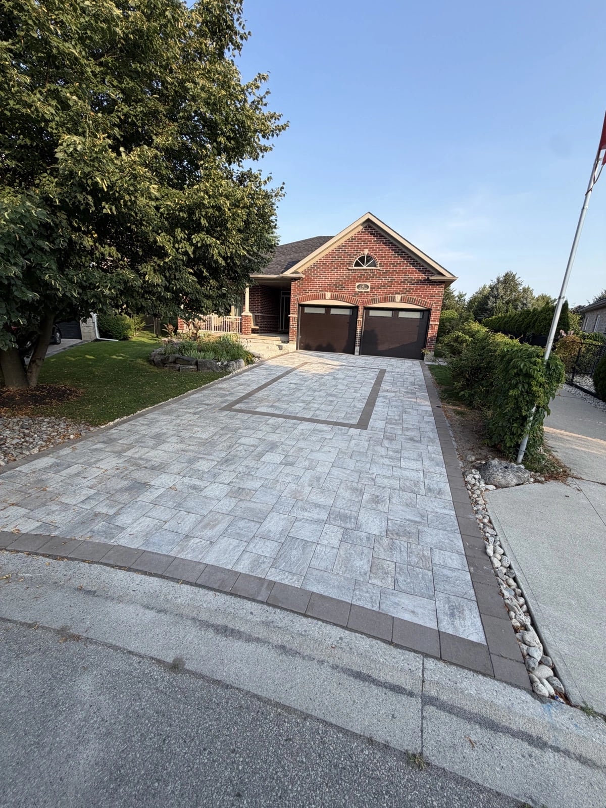 Wide residential interlocking driveway with charcoal border and rock garden edge, interlocking driveways Guelph by BCI Landscaping