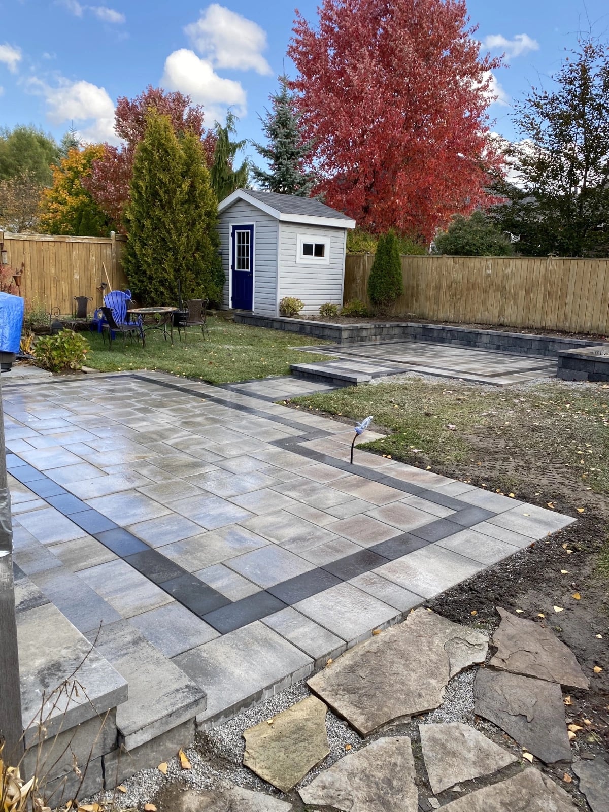 Multi-level backyard interlocking patio with charcoal border and raised platform, Guelph landscaping by BCI Landscaping