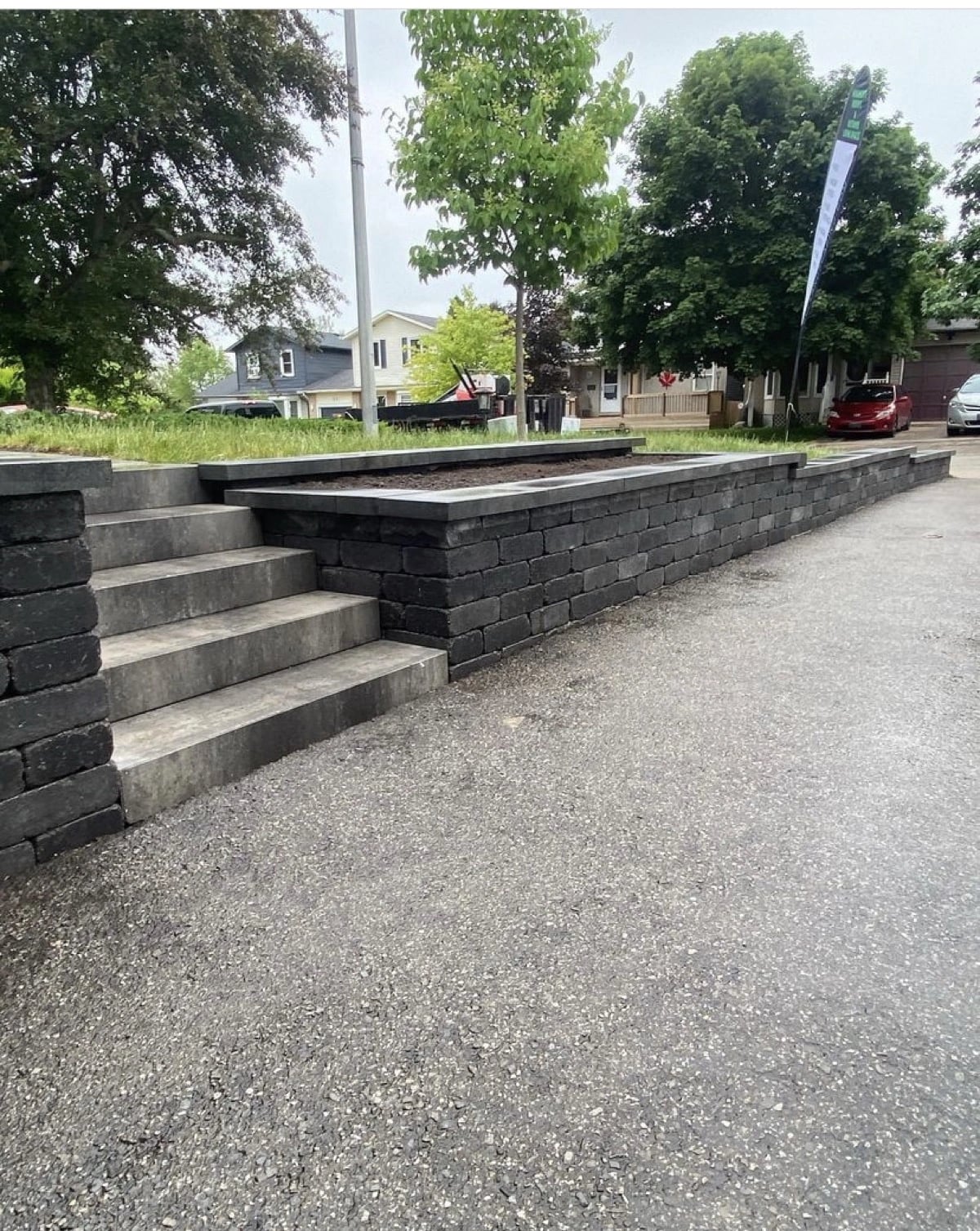 Dark charcoal interlock block retaining wall with integrated steps, retaining wall Guelph by BCI Landscaping
