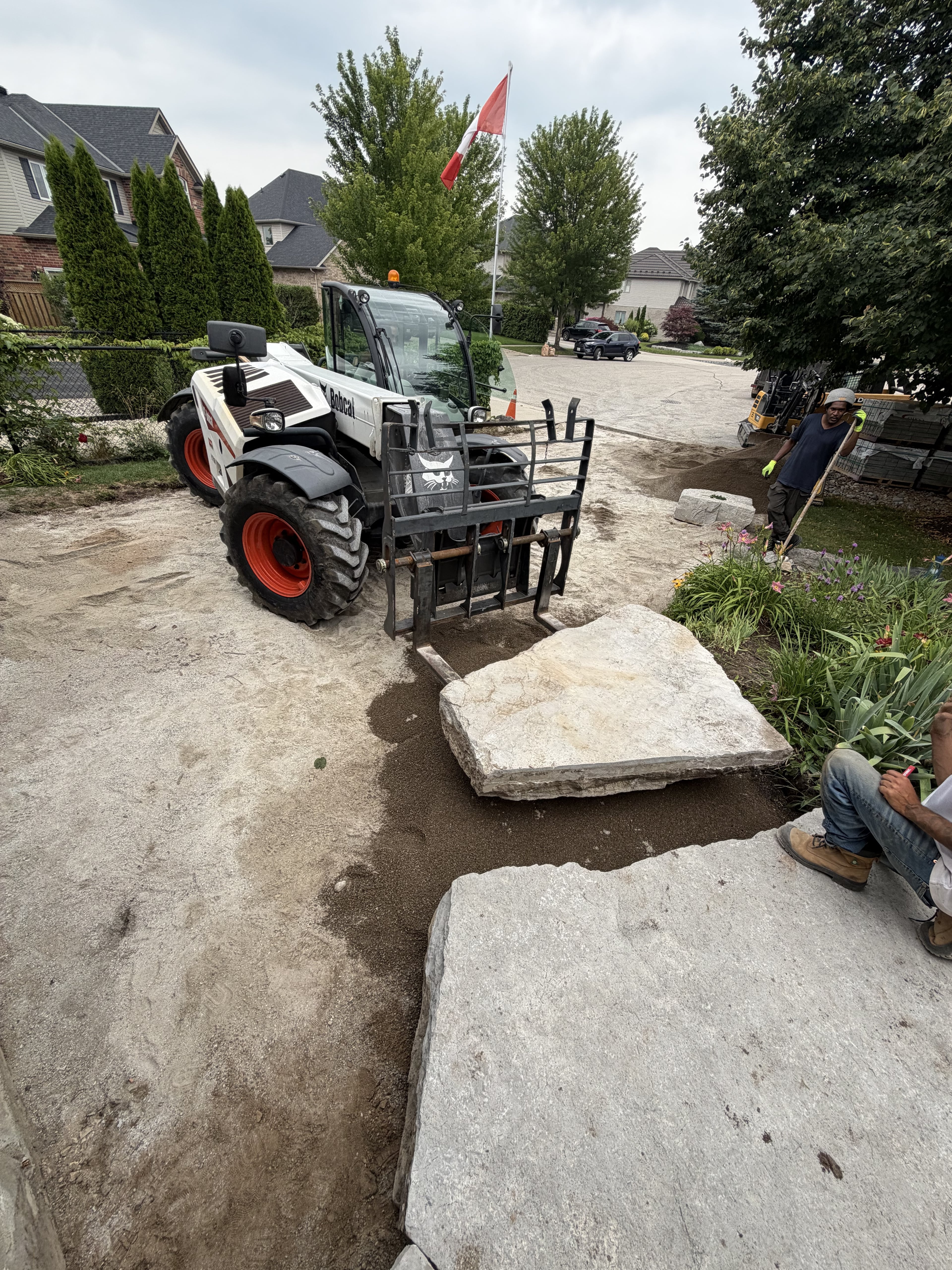 BCI Landscaping crew placing large armour stone with a telehandler on a Guelph landscaping project