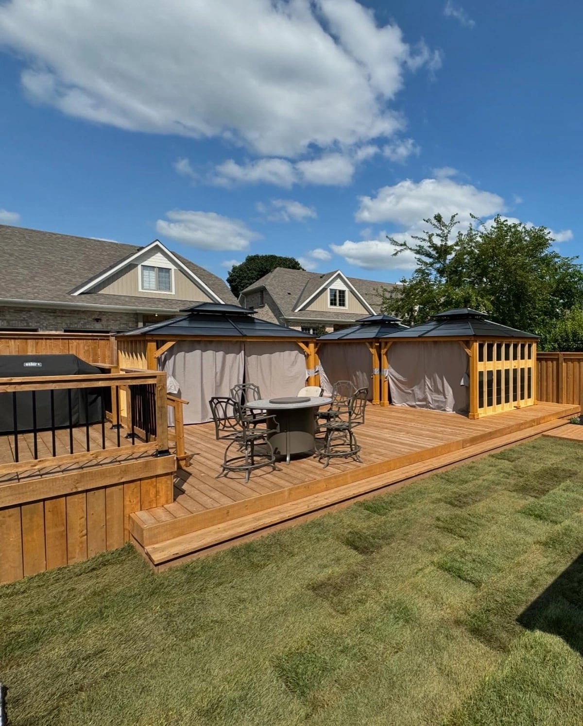 Large cedar deck with two steel-roof gazebos and outdoor dining area, deck builder Guelph by BCI Landscaping