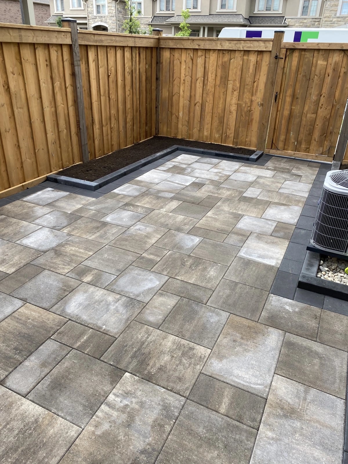 New cedar privacy fence enclosing a backyard patio and garden bed, fence builder Guelph by BCI Landscaping