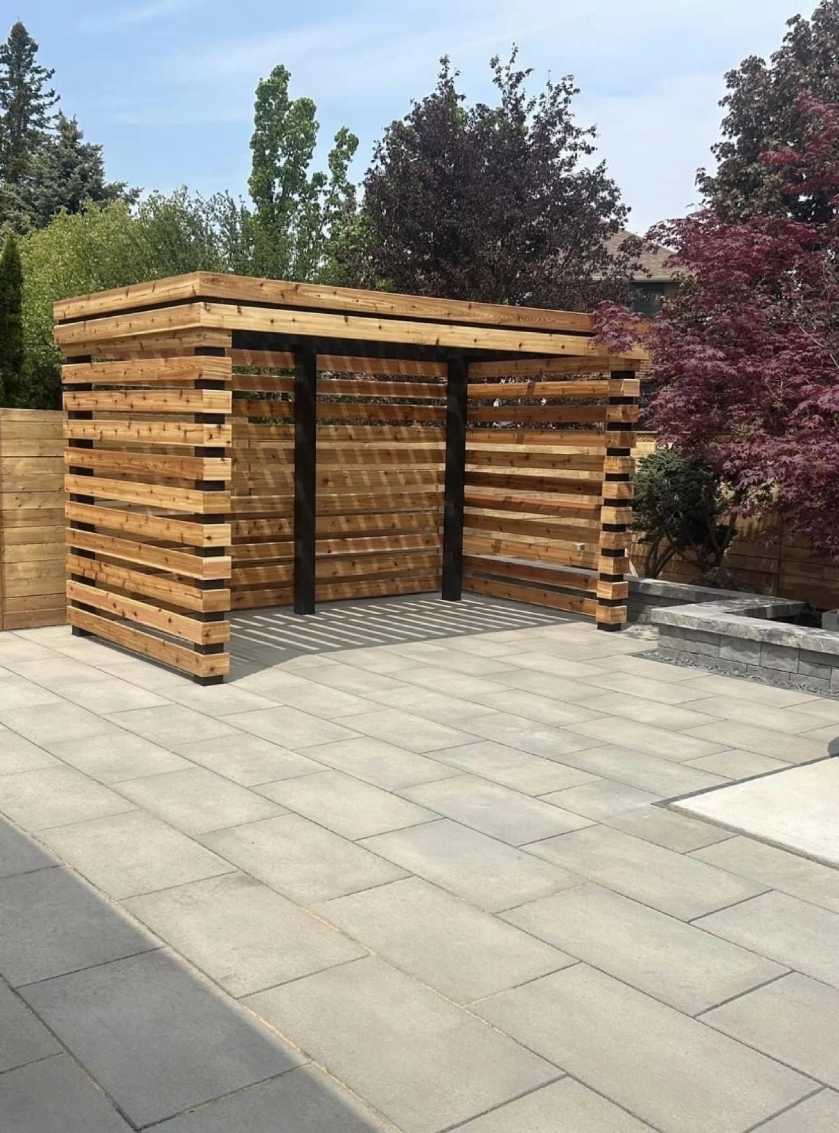 Modern cedar pergola with horizontal slat sides on an interlocking patio, pergola builder Guelph