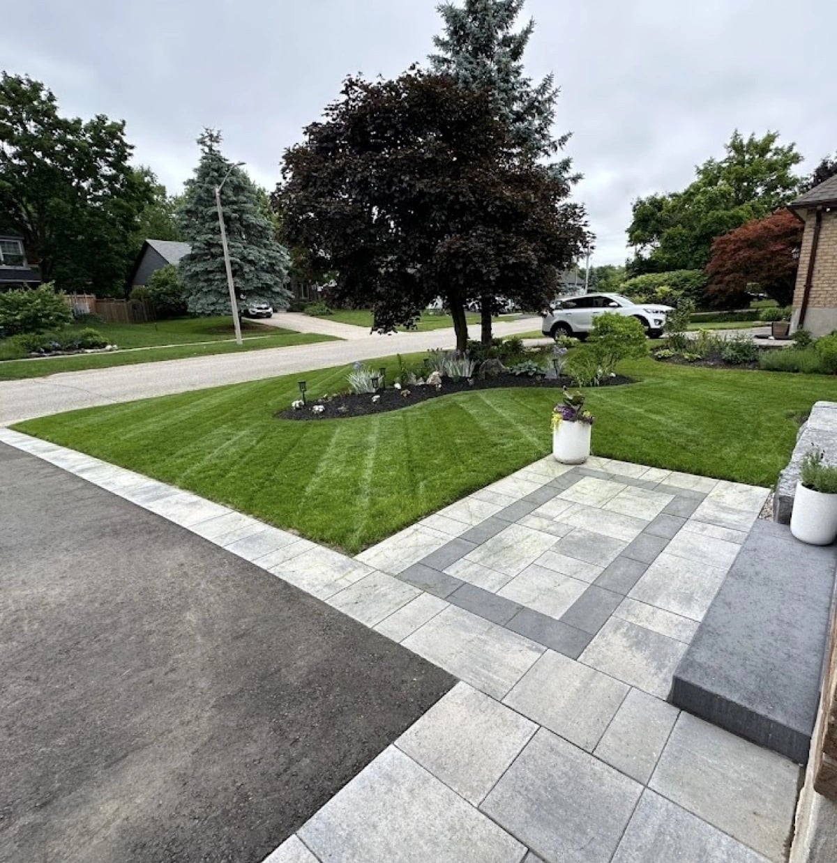Fresh sod installation in a front yard with interlock driveway and garden beds, Guelph landscaping by BCI Landscaping