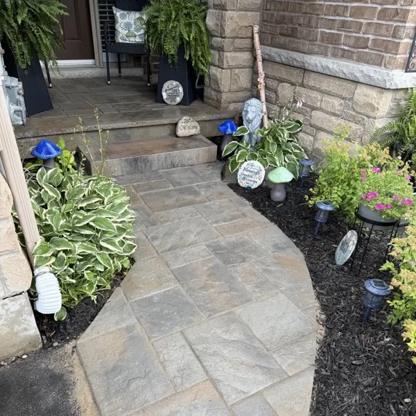 Curved interlocking walkway with garden beds and mulch leading to a front entrance, Guelph landscaping by BCI Landscaping